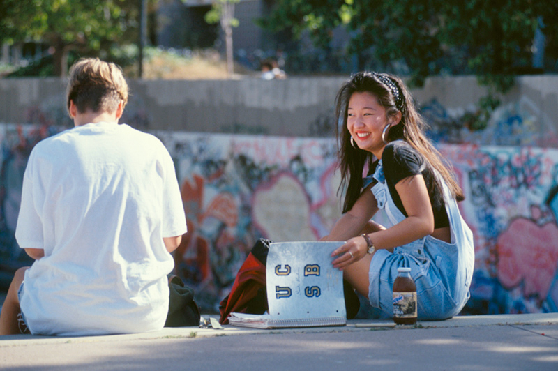 Two UCSB students interacting while sitting on a bench