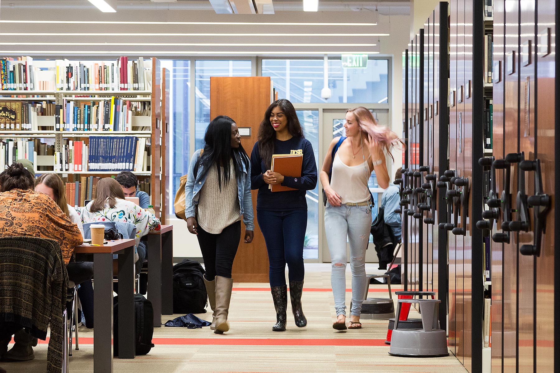 Three female students walking in library hallway