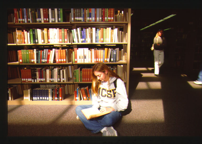 Female UCSB student reading sitting on the ucsb library floor 